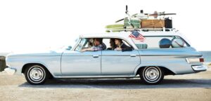 Vintage car with people enjoying a scenic drive, showcasing mid-20th-century transportation.